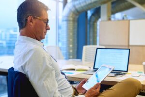 multitasking with wireless efficiency shot focussed businessman using his tablet while sitting his desk office 590464 45466