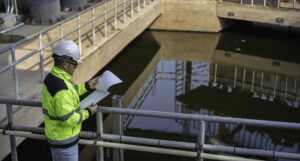 professional asian engineer inspecting water quality wastewater treatment plant he is carefully recording maintenance data clipboard industrial site safety survey 44277 31892 1