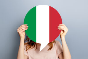 student girl holds blank white speech bubble with italian flag isolated grey studio background woman holding round information piece paper dialog
