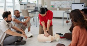 first aid cpr training people with dummy safety compliance health chest compression breathing paramedic course medical demonstration teaching emergency rescue technique office 590464 525199